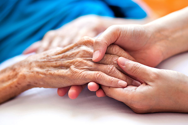 Female home caregiver talking with senior woman, sitting in living room and listening to her carefully.