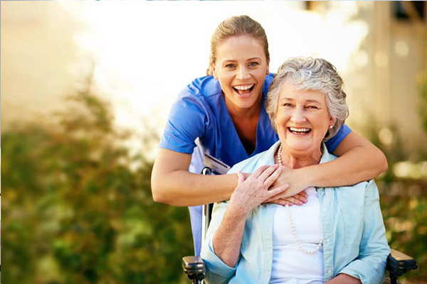 Female home caregiver talking with senior woman, sitting in living room and listening to her carefully.